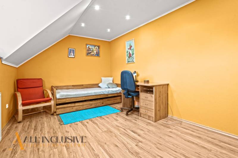 NA PREDAJ 6-IZBOVÝ POSCH. RODINNÝ DOM, HORNÉ SALIBY - Podkrovná izba s oranžovými stenami, nábytkom a podlahou s dreveným dekorom.