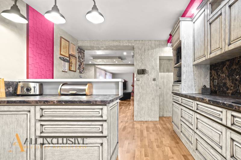 NA PREDAJ 6-IZBOVÝ POSCH. RODINNÝ DOM, HORNÉ SALIBY - Kuchyňa rodinného domu s podlahou s dreveným dekorom a výraznou ružovou stenou.