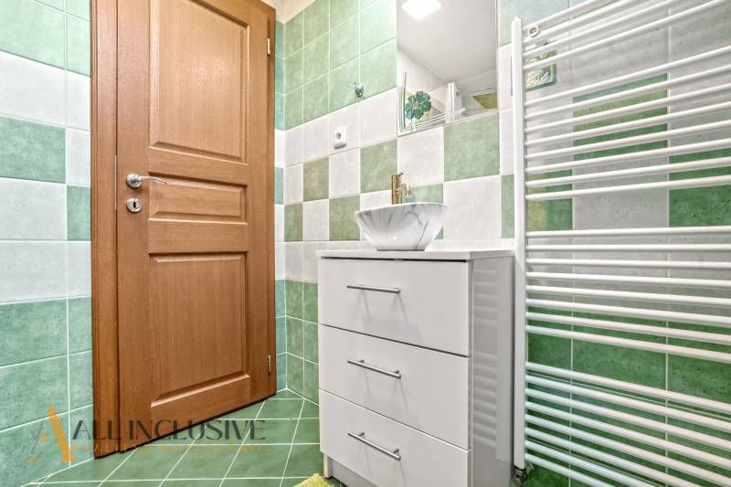 NA PREDAJ 6-IZBOVÝ POSCH. RODINNÝ DOM, HORNÉ SALIBY - Kúpeľňa s drevenými dverami, zelenými obkladmi a bielym nábytkom v rodinnom dome.