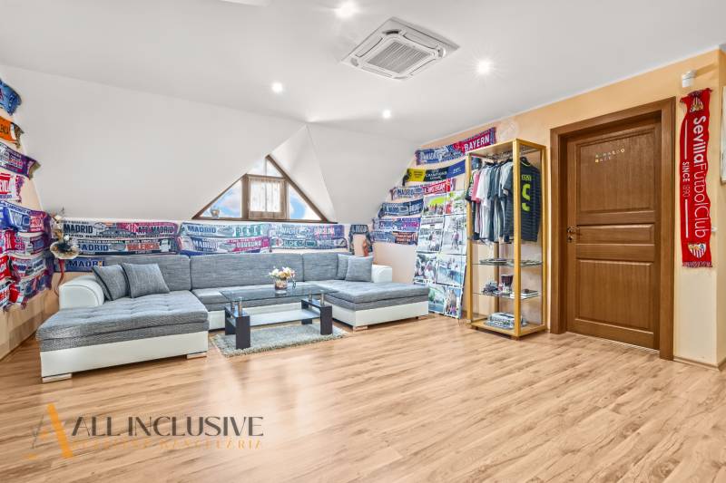 NA PREDAJ 6-IZBOVÝ POSCH. RODINNÝ DOM, HORNÉ SALIBY - Pohodlný obývací priestor v rodinnom dome s podlahou s dreveným dekorom a futbalovými šálmi.