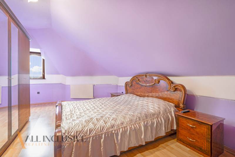 NA PREDAJ RODINNÉ DOMY S GARÁŽOU, DUNAJSKÁ STREDA - Fialová spálňa v rodinnom dome s drevenou posteľou a nočnými stolíkmi.