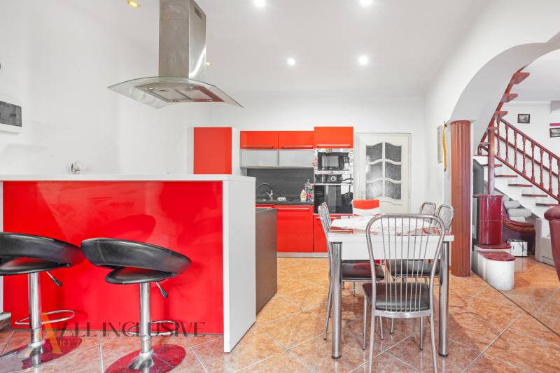 NA PREDAJ RODINNÉ DOMY S GARÁŽOU, DUNAJSKÁ STREDA - Kuchyňa v rodinnom dome s červenými skrinkami, jedálenským stolom a schodiskom.