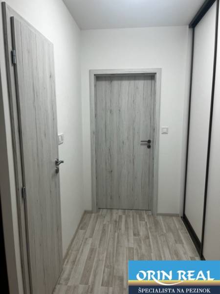 NOVÝ ZARIADENÝ KRÁSNY BYT S TERASOU - Úzka chodba so svetlými dverami a podlahou, ideálna pre 1-izbový byt na ulici Muškátová.