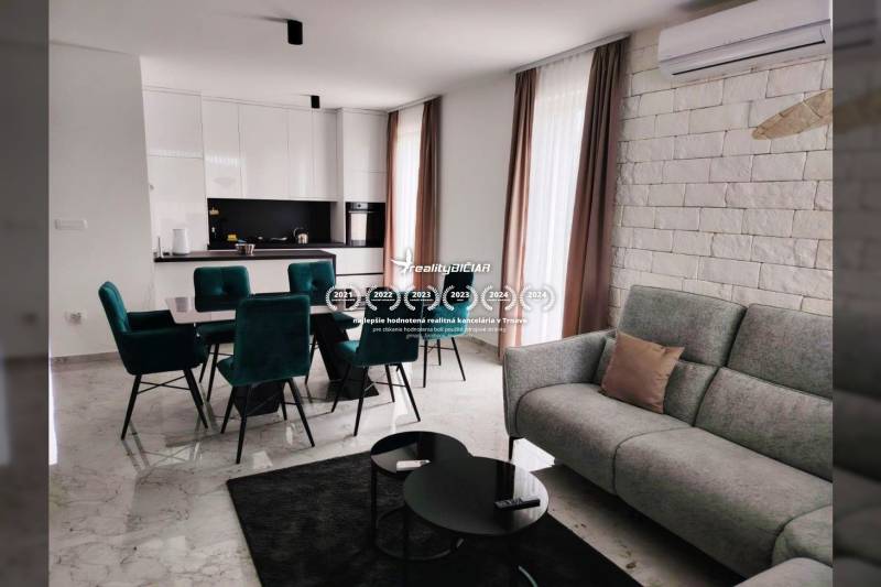 VRSI - dvojdom s bazénom a záhradou - Obývačka s kuchyňou v rodinnom dome; mramorová podlaha, biele skrinky, zelené stoličky.