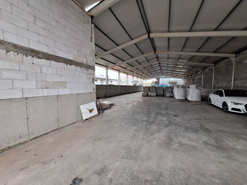 Na predaj sklad - hala, ul. Strojnícka, Prešov - V skladoch a halách vidno auto, stavebný materiál a prázdny priestor.