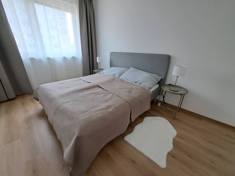 REZERVOVANÉ! Prenajmeme 3-izb. byt, 78 m2, Vráble, okr. Nitra - Spálňa v 3-izbovom byte s podlahou s dreveným dekorom, sivým posteľným čelom a koberečkom.