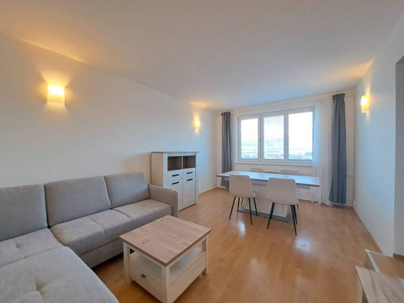 Prenájom pekného a priestranného 4-izbového bytu vo Svite - Obývačka v 4-izbovom byte s podlahou s dreveným dekorom a sivou sedačkou.