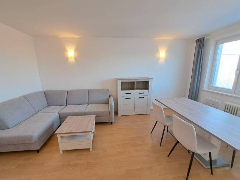 Prenájom pekného a priestranného 4-izbového bytu vo Svite - Obývacia izba v 4-izbovom byte s rohovou sedačkou a jedálenským stolom.