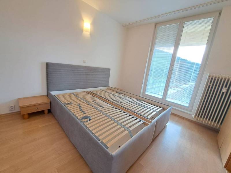 Prenájom pekného a priestranného 4-izbového bytu vo Svite - Spálňa v 4-izbovom byte s posteľou a nočným stolíkom, podlaha s dreveným dekorom.