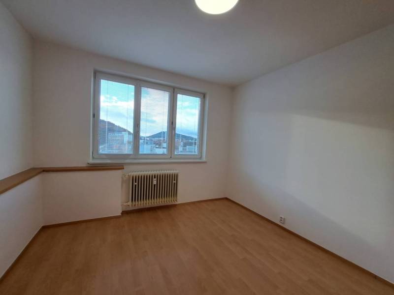 Prenájom pekného a priestranného 4-izbového bytu vo Svite - Miestnosť v 4-izbovom byte s podlahou s dreveným dekorom a veľkým oknom.