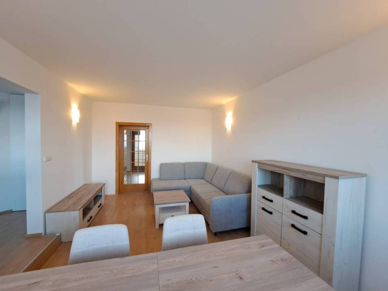 Prenájom pekného a priestranného 4-izbového bytu vo Svite - Obývacia izba v 4-izbovom byte s podlahou s dreveným dekorom a sivou sedačkou.