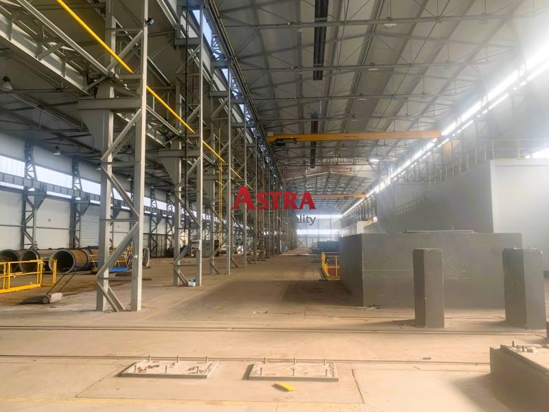 NA PRENÁJOM VÝROBNA A SKLADOVÁ HALA 6544 m², DOBŠINÁ - Výrobné priestory s kovovými štruktúrami a žeriavom vnútri haly.