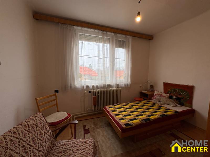 Exkluzívny PREDAJ 4 izbového rodinný domu s garážou, Zlatná na Ostrove - Izba s posteľou, kreslom a dekoratívnym kobercom na stene v rodinnom dome.