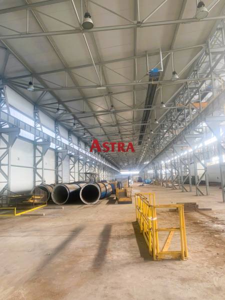 VÝROBNA A SKLADOVÁ HALA 6544 m2, DOBŠINÁ - Výrobné priestory s kovovými konštrukciami a potrubím, Dobšiná. Široká hala so žltými zábranami.