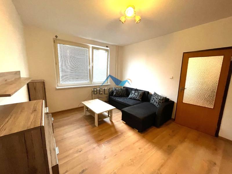 EXKLUZÍVNY PREDAJ - 1 izbový byt Revolučná Štvrť , Galanta - Obývacia izba v 1-izbovom byte so sedačkou a podlahou s dreveným dekorom.