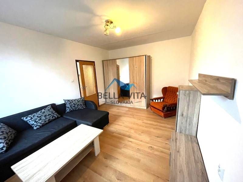 EXKLUZÍVNY PREDAJ - 1 izbový byt Revolučná Štvrť , Galanta - Obývacia izba v 1-izbovom byte s pohovkou a podlahou s dreveným dekorom.