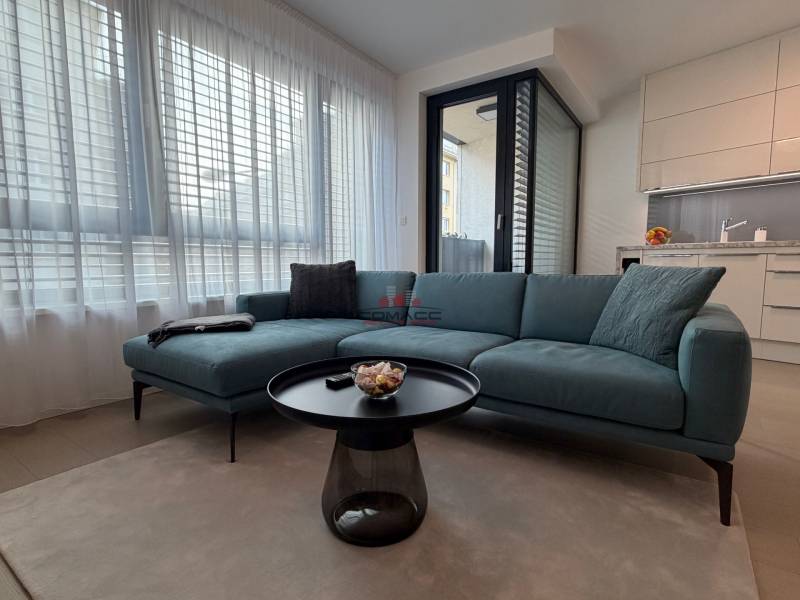 Exk. prenájom lux. 2 iz bytu Rezidencia Blumental - Obývačka s pohovkou, stolíkom a kuchynským kútom v 2-izbovom byte.