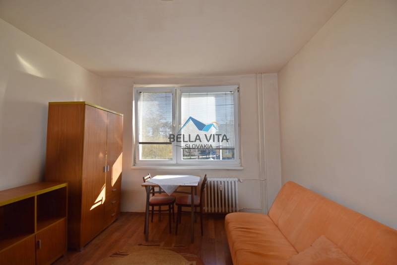 PRENÁJOM - Garsónka, Hlavná ulica Galanta - Garsónka s pohovkou, stolom a skriňou, podlaha s dreveným dekorom.