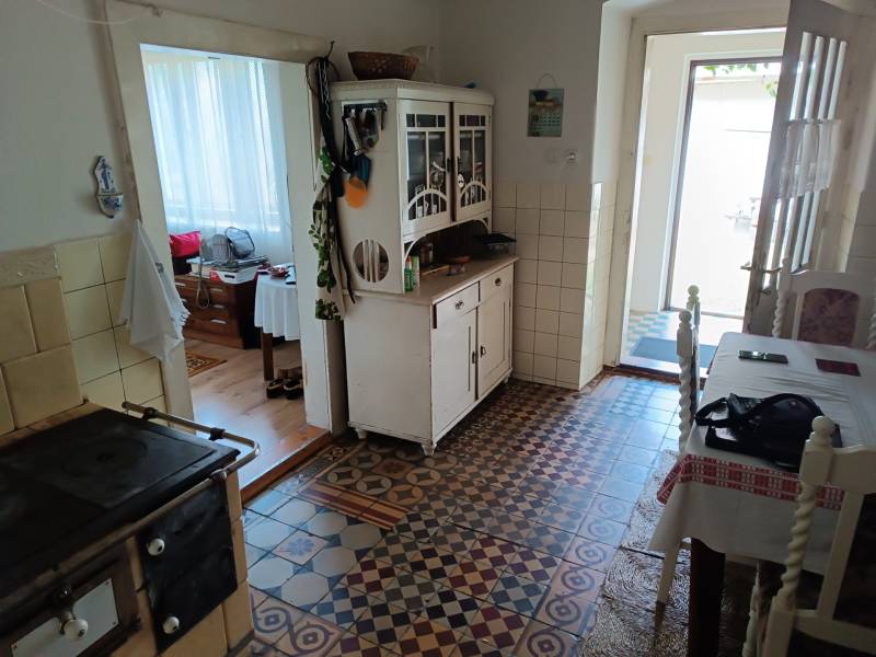 Hospodárska usadlosť s 3,6 hektárovým pozemkom na samote Nová Baňa - Vidíme kuchyňu s kachľovou dlažbou, sporák a starožitnú komodu v rodinnom dome.