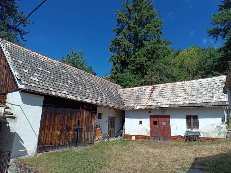 Hospodárska usadlosť s 3,6 hektárovým pozemkom na samote Nová Baňa - Tradičný rodinný dom so starou šindľovou strechou a drevenými dverami na dvore.