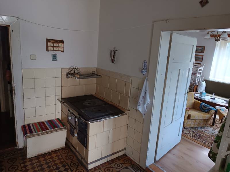 Hospodárska usadlosť s 3,6 hektárovým pozemkom na samote Nová Baňa - Starší sporák v kuchyni rodinného domu, vedúci do obývacej izby s nábytkom.