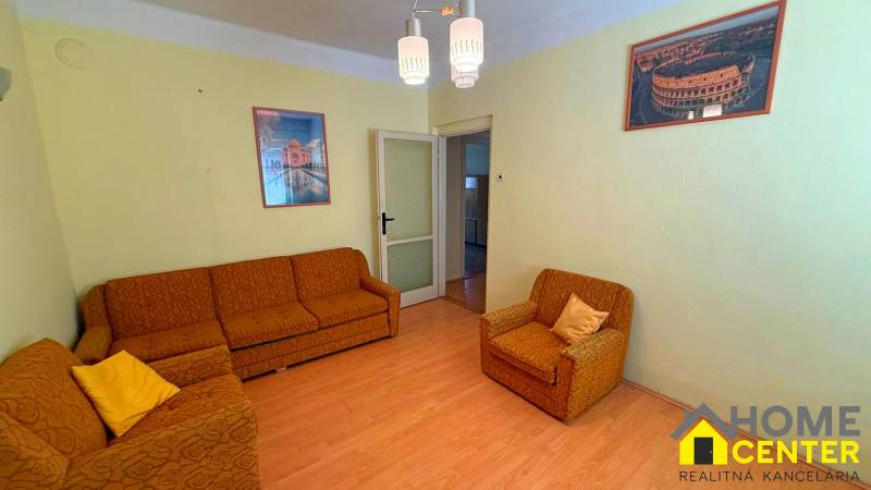 NA PREDAJ 5 izbový rodinný dom s veľkou záhradou v obci Iža - Obývacia izba v rodinnom dome s oranžovým nábytkom a podlahou s dreveným dekorom.