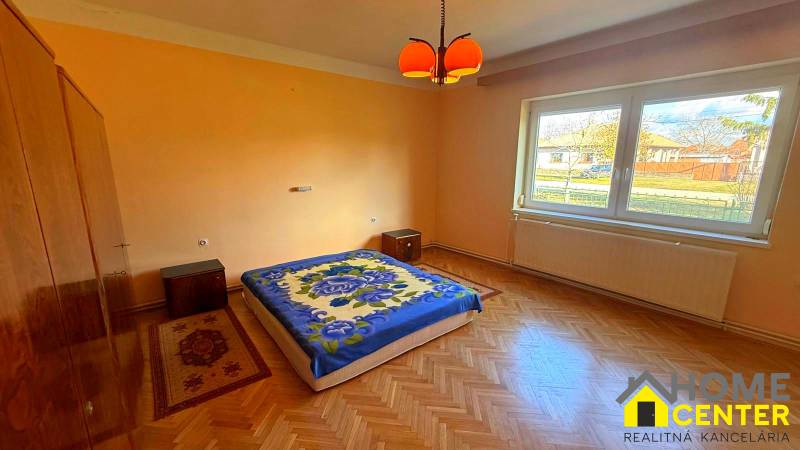 NA PREDAJ 5 izbový rodinný dom s veľkou záhradou v obci Iža - Spálňa v rodinnom dome s podlahou s dreveným dekorom a oranžovými stenami.