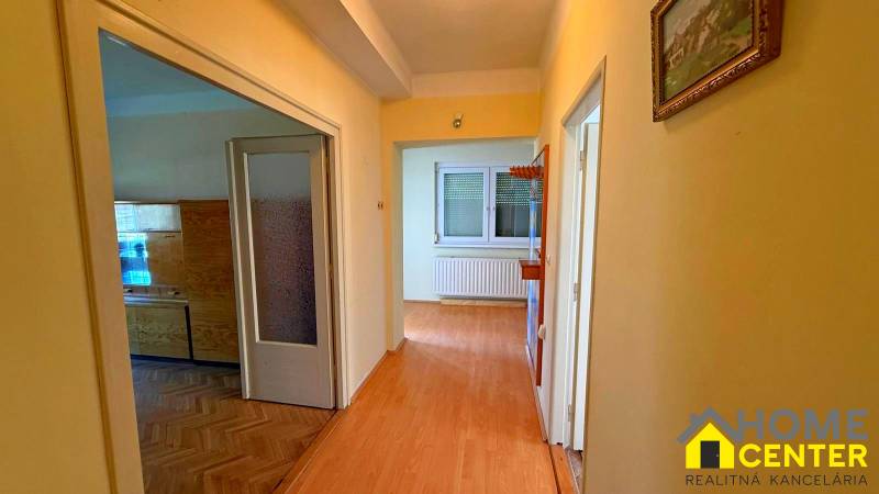 NA PREDAJ 5 izbový rodinný dom s veľkou záhradou v obci Iža - Chodba v rodinnom dome s podlahou s dreveným dekorom a obrazom na stene.