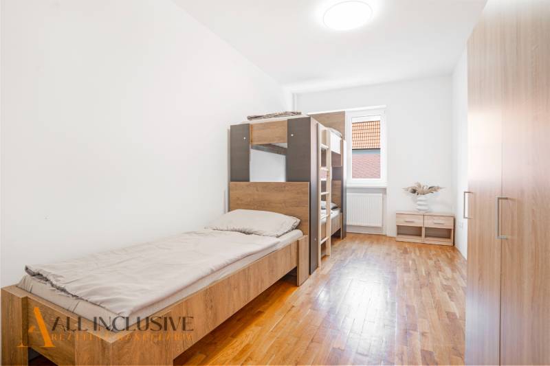 Na predaj 7-izb. RD s obchod. priestorom, Dun. Streda - Interiér spálne v budove s posteľami a podlahou s dreveným dekorom.