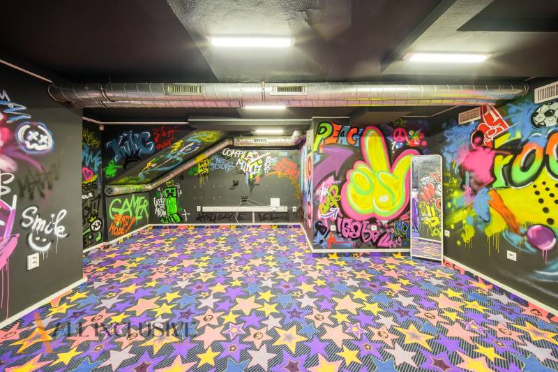 Na predaj 7-izb. RD s obchod. priestorom, Dun. Streda - Interiér budovy s graffiti na stenách a farebným kobercom s hviezdami.