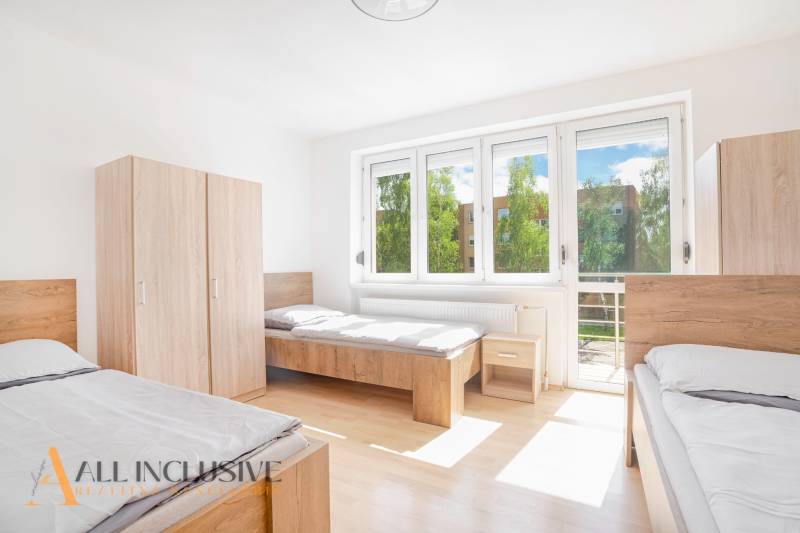 Na predaj 7-izb. RD s obchod. priestorom, Dun. Streda - Svetlá izba s tromi posteľami, bielymi stenami, skriňami a veľkými oknami.