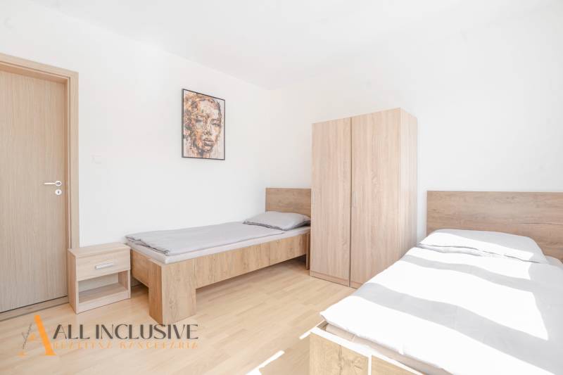 Na predaj 7-izb. RD s obchod. priestorom, Dun. Streda - Spálňa s dvomi posteľami a nábytkom, podlaha s dreveným dekorom, obraz na stene.