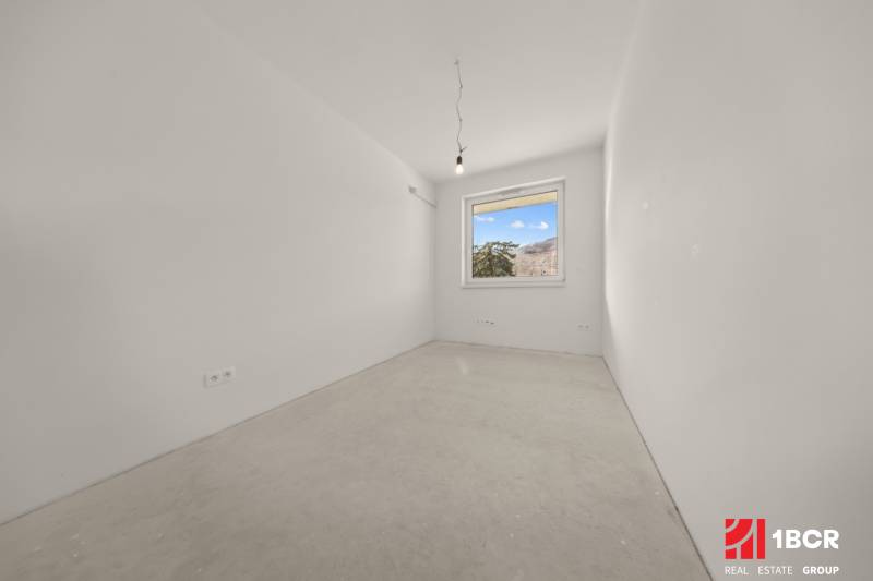 PROJEKT POD VINICOU | 4-IZB. BYT, UZAVRETÝ AREÁL, HOLOBYT, NOVOSTAVBA - Prázdna izba s oknom, jednoduché steny, súčasť 4-izbového bytu.