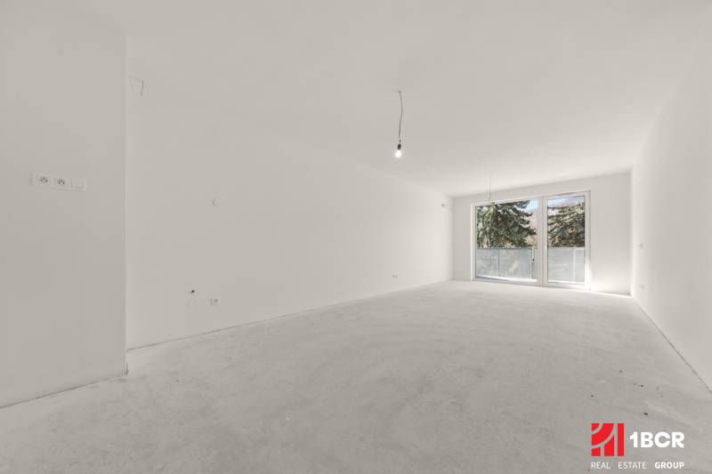 PROJEKT POD VINICOU | 4-IZB. BYT, UZAVRETÝ AREÁL, HOLOBYT, NOVOSTAVBA - Priestranná miestnosť v 4-izbovom byte s veľkým francúzskym oknom a bielymi stenami.