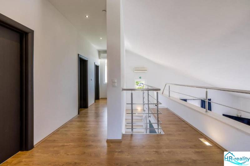 Kaštela(HR)-moderná vila s krásnym výhľadom - Interiér Vily s bielymi stenami, podlahou s dreveným dekorom a zábradlím.