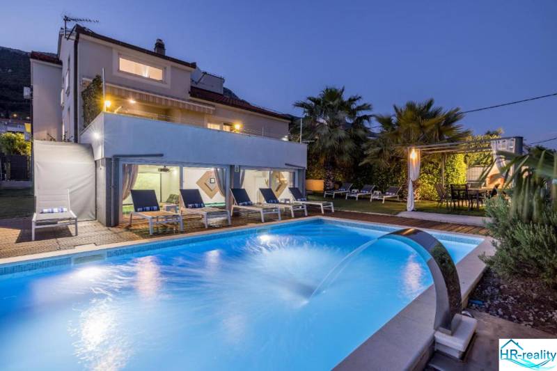 Kaštela(HR)-moderná vila s krásnym výhľadom - Vila v Kaštela s osvetleným bazénom, ležadlami a palmami v záhrade pri súmraku.