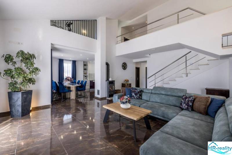 Kaštela(HR)-moderná vila s krásnym výhľadom - Obývačka vile s pohodlnou sedačkou, jedálňou a schodiskom, podlaha s dreveným dekorom.