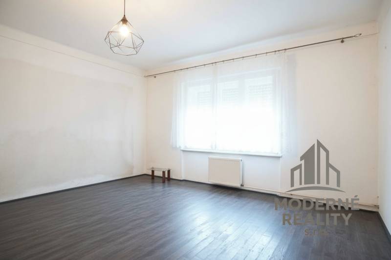 Rodinný dom v centre s garážou, Dvory nad Žitavou, 798m2 - Izba v rodinnom dome s podlahou s dreveným dekorom a veľkým oknom.