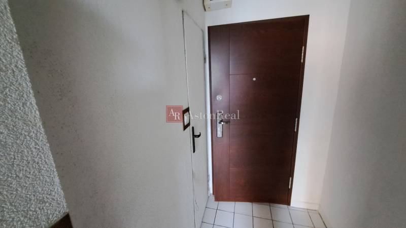 PREDAJ: 1 izbový byt - 37m2, s loggiou, Ružomberok - Za dráhou - Vstupné dvere do 1-izbového bytu s dlažbou a bielymi stenami.