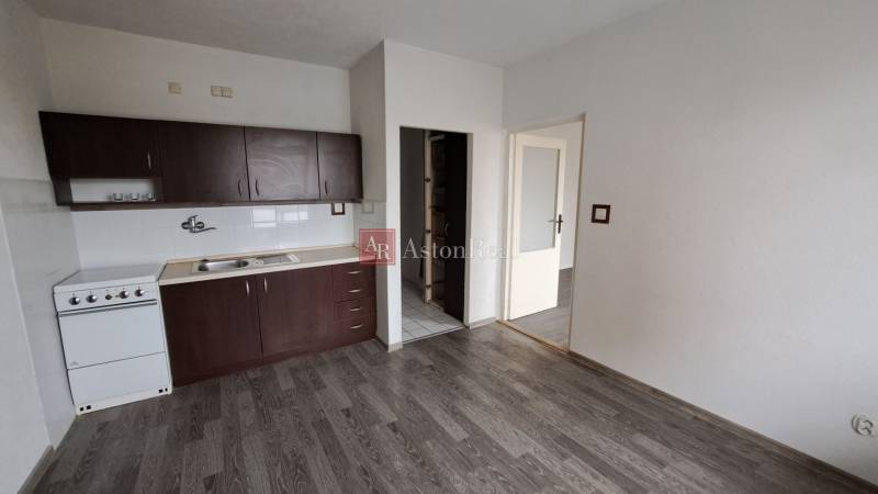 PREDAJ: 1 izbový byt - 37m2, s loggiou, Ružomberok - Za dráhou - Kuchyňa s tmavými skrinkami a podlahou s dreveným dekorom v 1-izbovom byte.