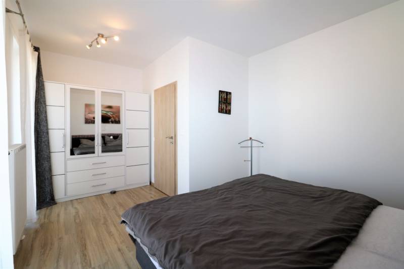 NUERA︱ SLNEČNICE- slnečný 2izbový byt s výhľadom na hrad - Spálňa v 2-izbovom byte s podlahou s dreveným dekorom, šatníkom a posteľou.