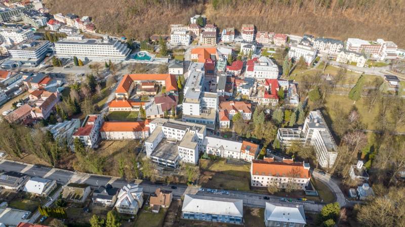 Exkluzívny investičný  pozemok Trenčianske Teplice, 1244m2 - Letecký pohľad na Trenčianske Teplice, Hurbanovu ulicu s komerčnými pozemkami a okolím.