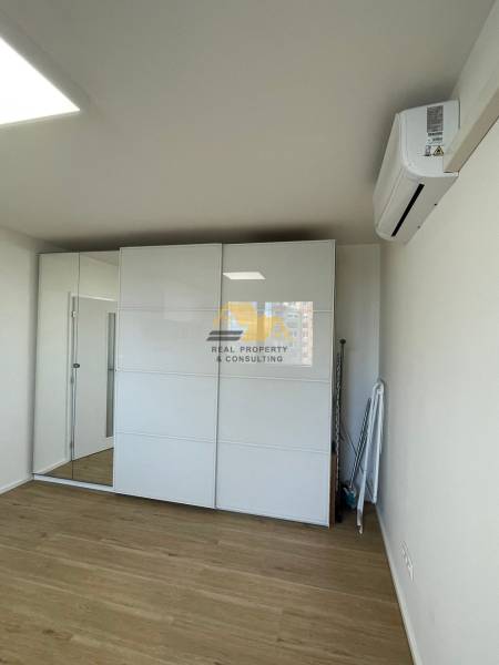 Prenajmem 1 izbový byt na Nábrežnej ulici v Nových Zámkoch - Jednoizbový byt so zrkadlovou skriňou a podlahou s dreveným dekorom.