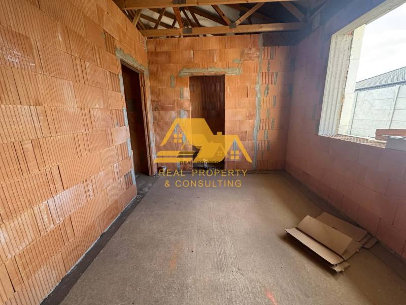 Predám novostavbu rodinného domu s garážou v Nových Zámkoch - Interiér rozostavaného rodinného domu s obnaženými tehlami a stavebnými materiálmi.