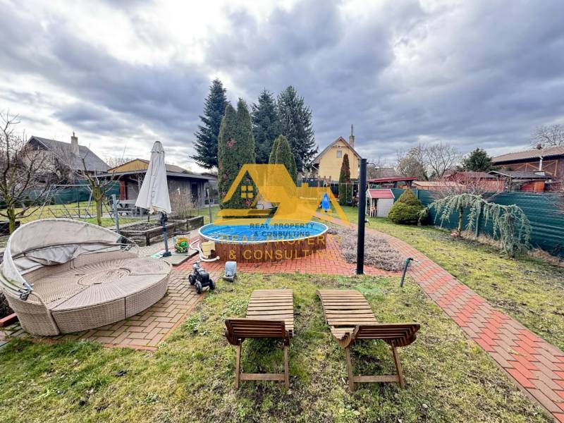 Predám peknú chatu na celoročné bývanie v Nových zámkoch - Záhrada pri chate s bazénom na ulici v Nových Zámkoch, obklopená udržiavanou zeleňou.