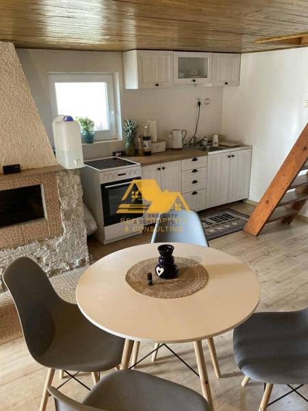 Predám peknú chatu na celoročné bývanie v Nových zámkoch - Interiér chaty so stolom, štyrmi stoličkami a kuchynským kútom s podlahou s dreveným dekorom.