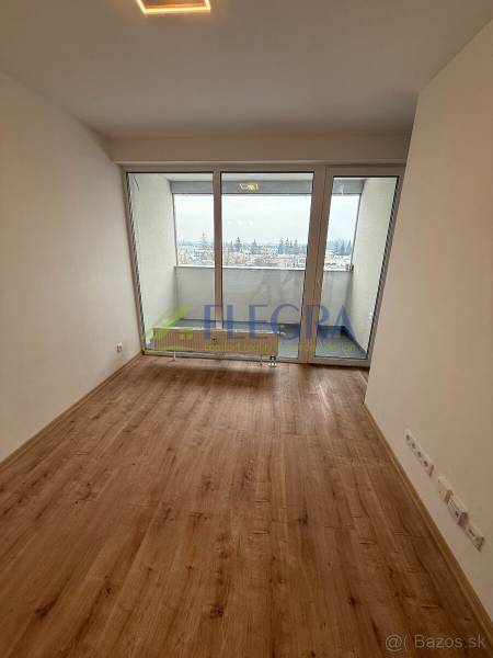 Na predaj 1,5-izbový byt v novostavbe GREENSIDE Trebišov - Obývacia izba v 1-izbovom byte s podlahou s dreveným dekorom a veľkými oknami.