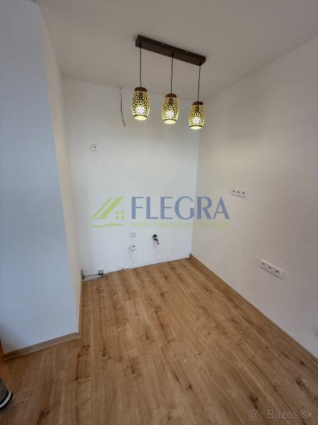 Na predaj 1,5-izbový byt v novostavbe GREENSIDE Trebišov - Interiér 1-izbového bytu s podlahou s dreveným dekorom a závesnými svietidlami.