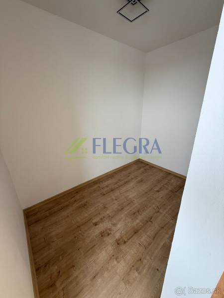 Na predaj 1,5-izbový byt v novostavbe GREENSIDE Trebišov - Prázdna miestnosť v 1-izbovom byte s podlahou s dreveným dekorom, biele steny.