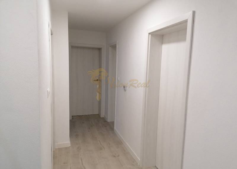 Rodinný dom v obci Bernolákovo, po kompletnej rekonštrukcii - Úzky chodba v rodinnom dome s bielymi stenami a podlahou s dreveným dekorom.